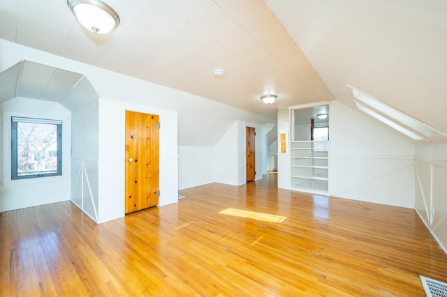 bonus room with vaulted ceiling, wood finished floors, and visible vents