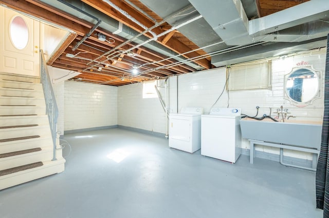 below grade area featuring stairs, a sink, and washing machine and dryer