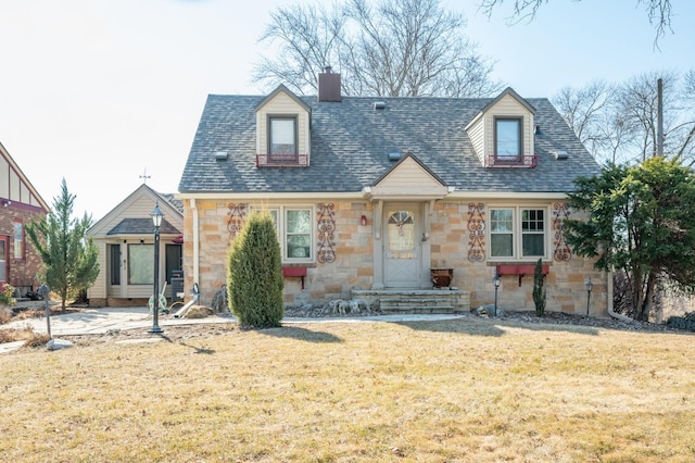 cape cod house featuring stone siding, roof with shingles, a chimney, and a front lawn