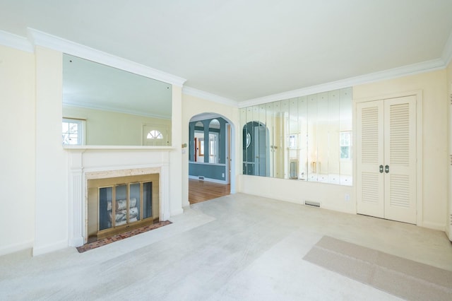 living room featuring arched walkways, a fireplace with flush hearth, carpet flooring, visible vents, and crown molding