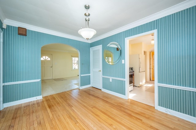 unfurnished room with ornamental molding, arched walkways, hardwood / wood-style flooring, and wallpapered walls