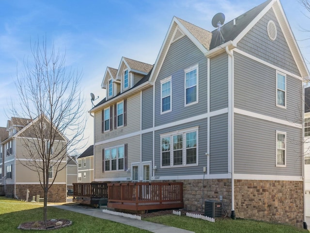 rear view of property featuring stone siding, a wooden deck, central AC, and a yard