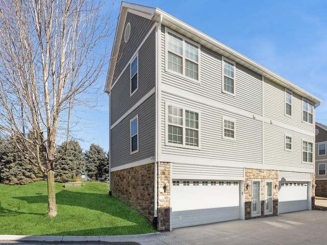 view of home's exterior featuring concrete driveway, stone siding, a yard, and an attached garage