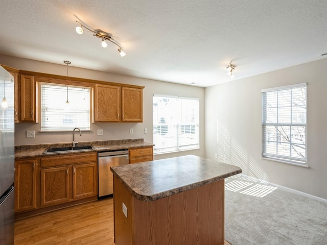 kitchen featuring stainless steel dishwasher, dark countertops, a sink, and brown cabinets