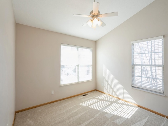 unfurnished room featuring lofted ceiling, a wealth of natural light, visible vents, and carpet flooring