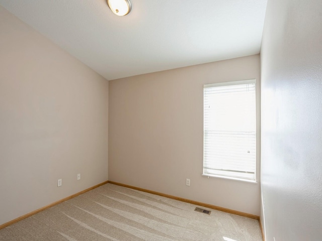 spare room with baseboards, visible vents, and light colored carpet