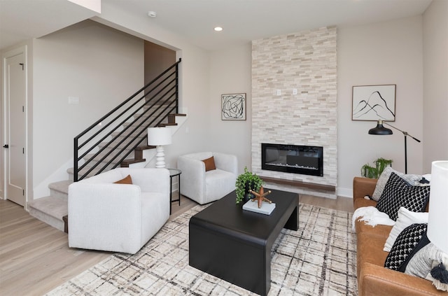 living room featuring recessed lighting, stairway, a tiled fireplace, and wood finished floors