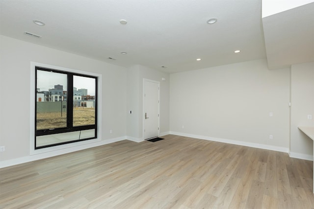 empty room featuring recessed lighting, baseboards, and light wood finished floors