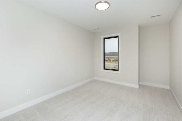 spare room with light carpet, visible vents, and baseboards