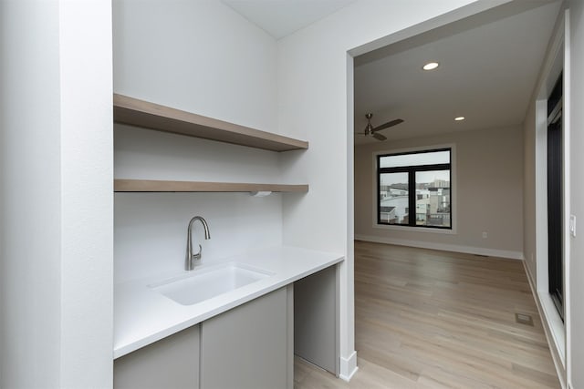 kitchen with open shelves, light countertops, light wood-style floors, a sink, and modern cabinets