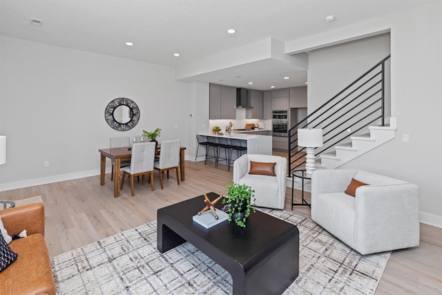 1160 Murphy St, Des Moines, IA 50309 - living room featuring stairway, light wood-style flooring, baseboards, and recessed lighting