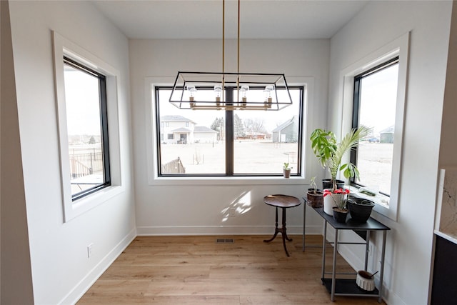 dining area with light wood-type flooring, visible vents, baseboards, and a notable chandelier