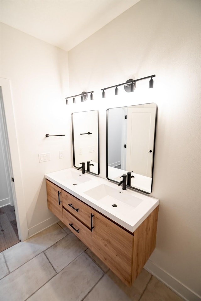 bathroom featuring double vanity, a sink, and baseboards