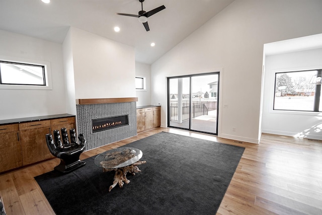 unfurnished living room featuring light wood-type flooring, baseboards, recessed lighting, and a tile fireplace