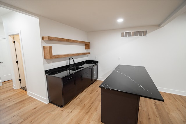 kitchen with dark countertops, visible vents, open shelves, and a sink