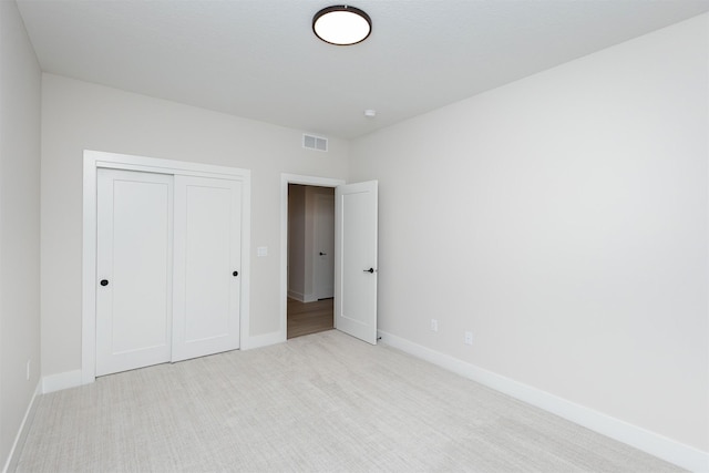 unfurnished bedroom with carpet floors, a closet, visible vents, and baseboards