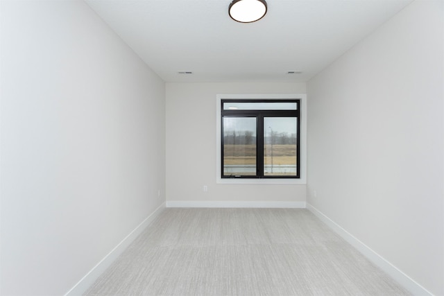 spare room with light colored carpet, visible vents, and baseboards