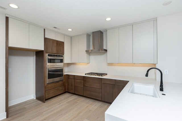 1166 Murphy St, Des Moines, IA 50309 - kitchen with wall chimney range hood, a sink, stainless steel appliances, light wood-style floors, and recessed lighting