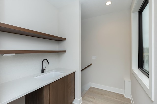 bar featuring recessed lighting, a sink, light wood-style flooring, and baseboards