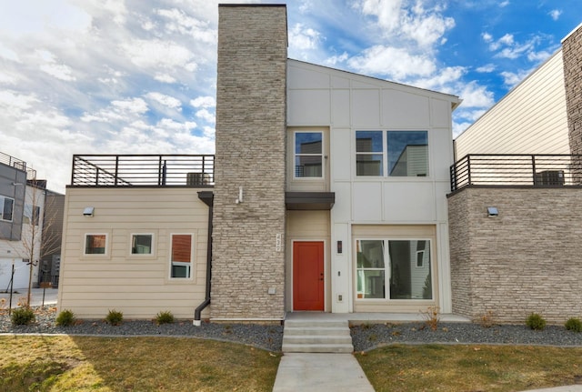 contemporary house with a balcony and a front lawn