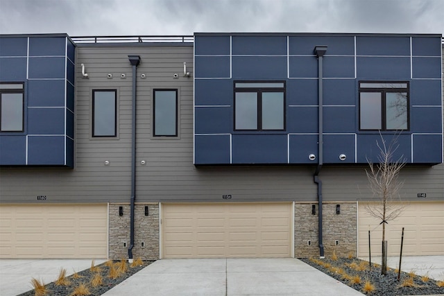 exterior space with stone siding, driveway, and an attached garage