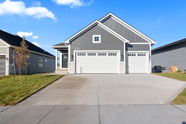 craftsman house featuring central AC, driveway, stone siding, board and batten siding, and a front yard