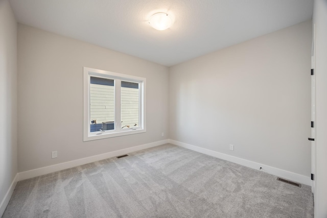 carpeted spare room with visible vents and baseboards