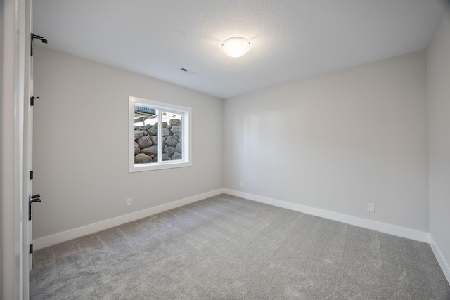 unfurnished room with carpet floors, visible vents, and baseboards