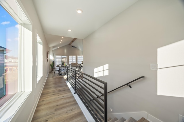 stairway featuring baseboards, vaulted ceiling, wood finished floors, and recessed lighting