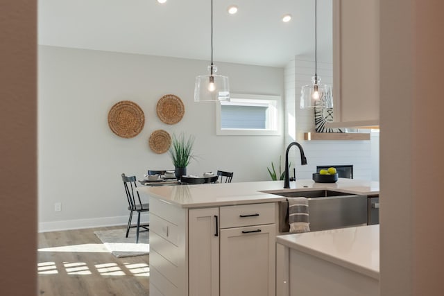 kitchen featuring a sink, white cabinets, light countertops, backsplash, and light wood finished floors