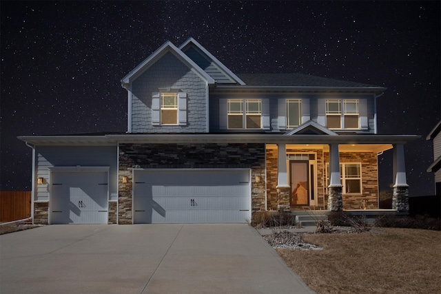 craftsman-style home featuring an attached garage, concrete driveway, covered porch, and stone siding