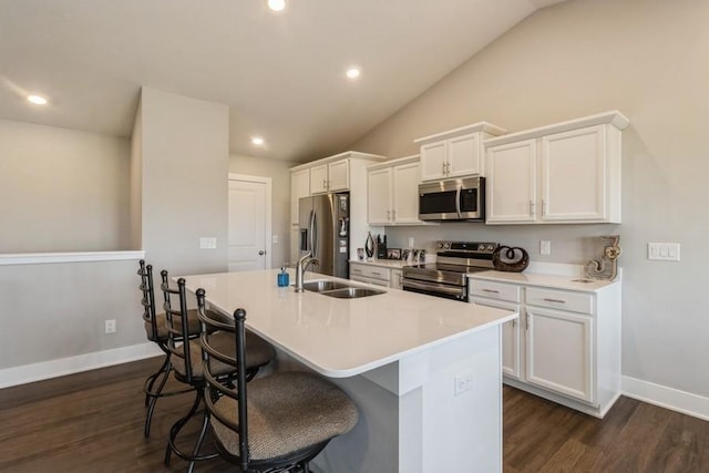 kitchen with dark wood finished floors, a breakfast bar area, stainless steel appliances, lofted ceiling, and a kitchen island with sink