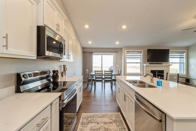 kitchen with stainless steel appliances, open floor plan, white cabinetry, and a sink