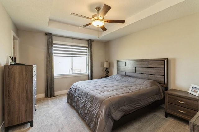 bedroom featuring baseboards, ceiling fan, a raised ceiling, and light colored carpet