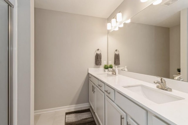 full bath featuring double vanity, a sink, visible vents, and baseboards