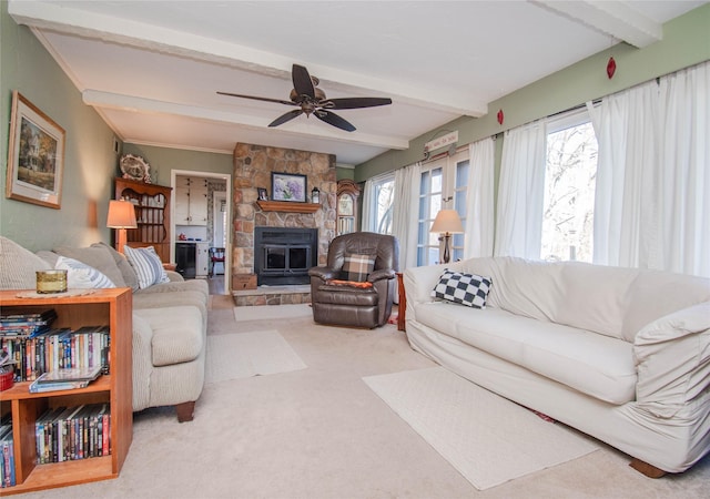 carpeted living area featuring a stone fireplace, a ceiling fan, beam ceiling, and a healthy amount of sunlight