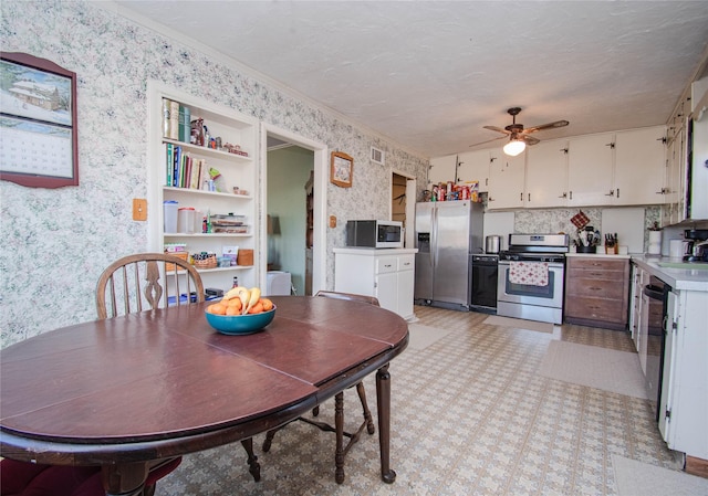 dining area with wallpapered walls, visible vents, ceiling fan, ornamental molding, and a textured ceiling