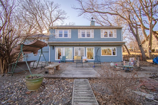 back of property featuring a chimney, a patio, and brick siding