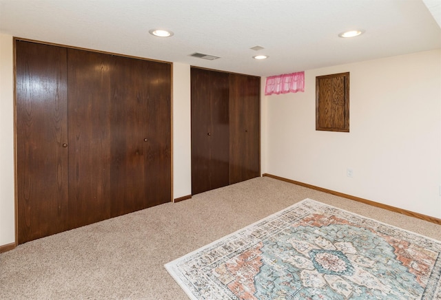 carpeted bedroom featuring baseboards, visible vents, two closets, and recessed lighting