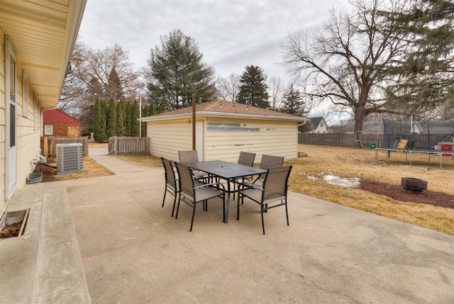 view of patio featuring central air condition unit, a fenced backyard, a trampoline, and outdoor dining space