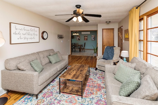 living room featuring ceiling fan, a textured ceiling, and wood finished floors