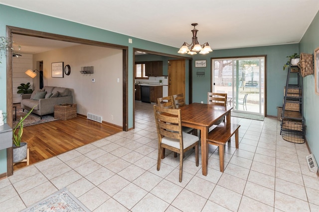 dining area with light tile patterned floors, visible vents, a chandelier, and baseboards