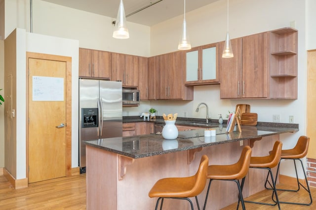 kitchen featuring open shelves, stainless steel appliances, brown cabinetry, dark stone counters, and a peninsula