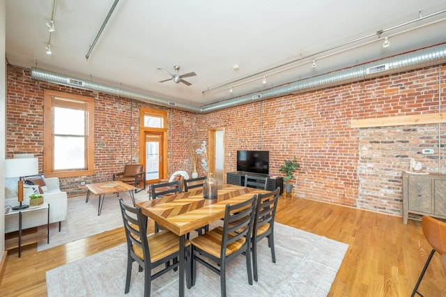 dining space featuring track lighting and brick wall