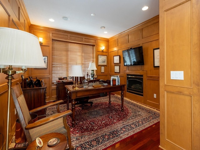 office featuring a fireplace, ornamental molding, a decorative wall, and wood finished floors