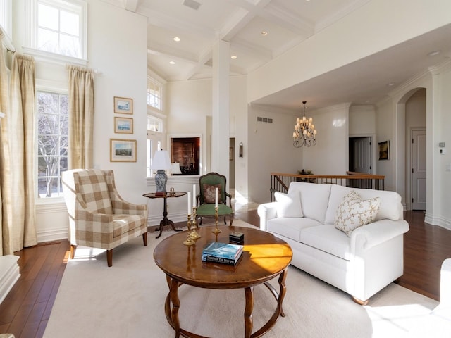 living area with visible vents, a high ceiling, wood finished floors, and beam ceiling