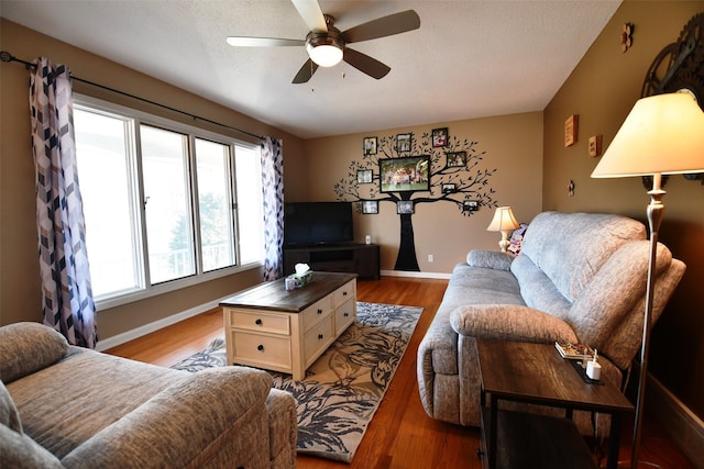 living area featuring a textured ceiling, a ceiling fan, light wood-style flooring, and baseboards