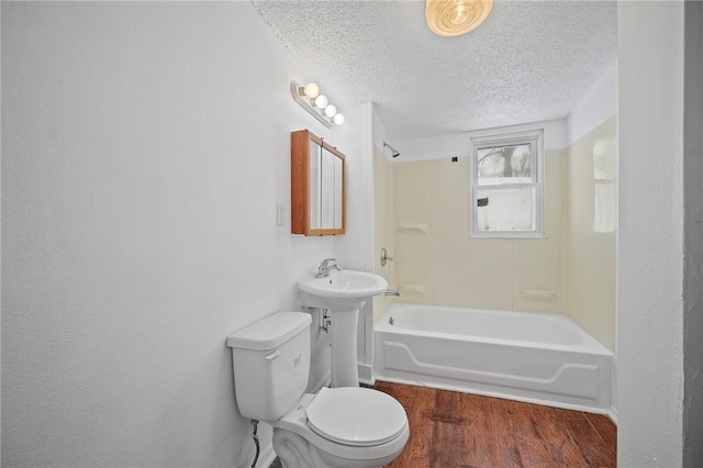 full bathroom with bathing tub / shower combination, a textured ceiling, toilet, and wood finished floors