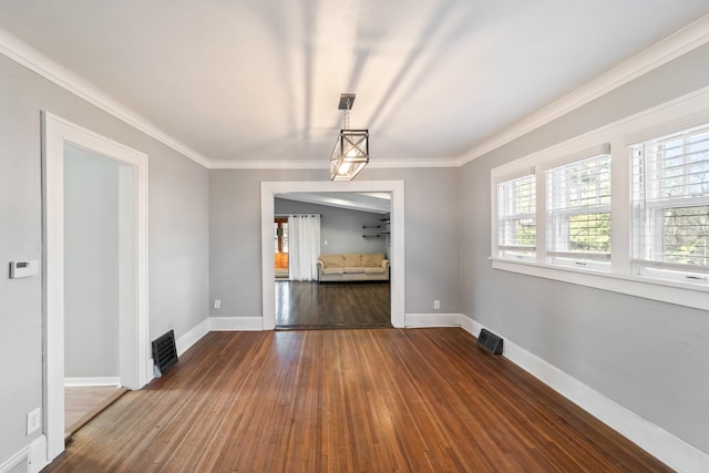 unfurnished dining area featuring dark wood-style floors, visible vents, baseboards, and ornamental molding