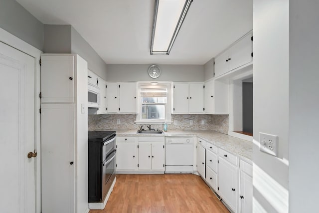 kitchen with white appliances, tasteful backsplash, light wood-style flooring, light countertops, and white cabinetry